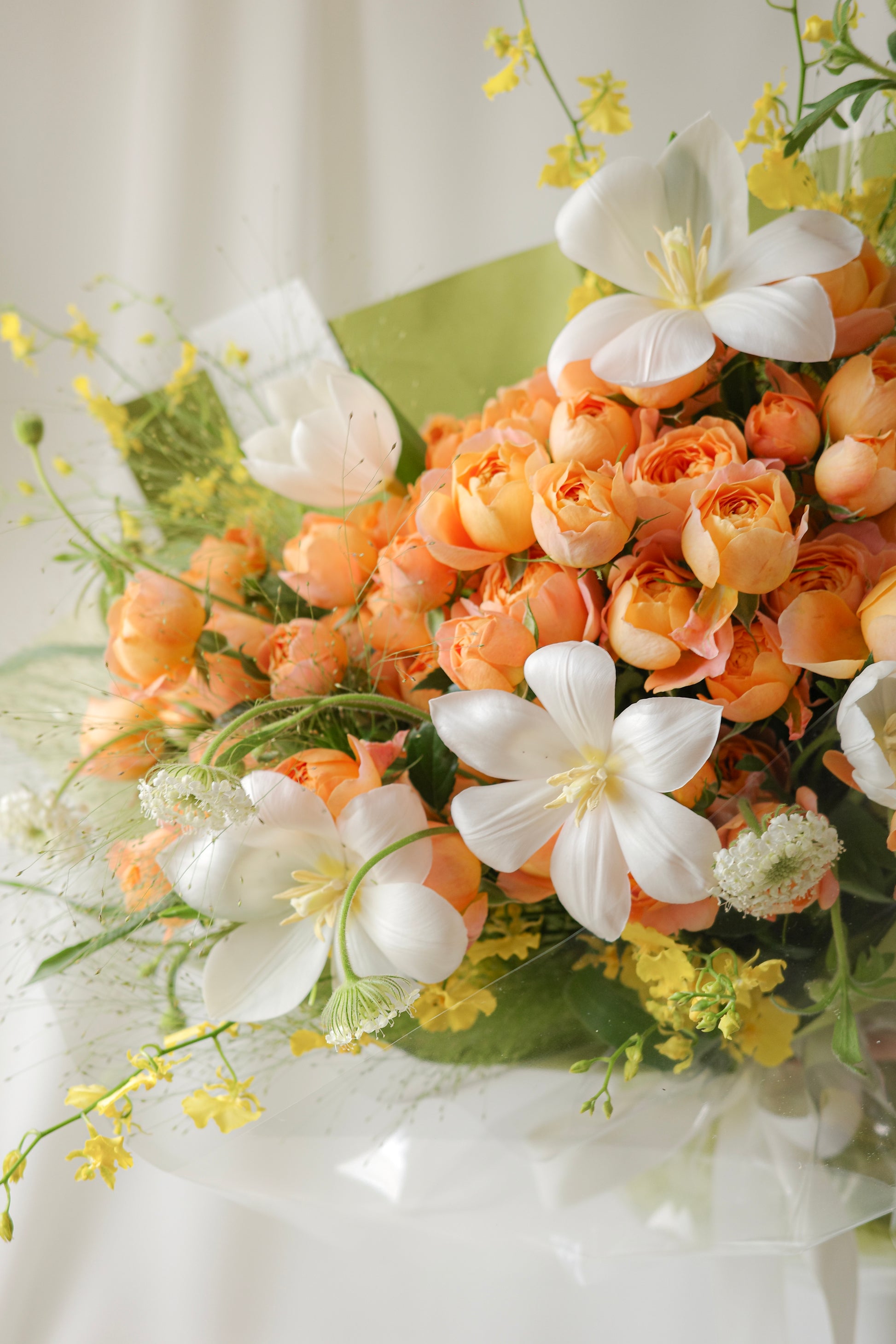 Fresh bouquet of orange roses, white blooms, and yellow accents with airy blooms, a cheerful arrangement perfect for birthdays and celebrations.
