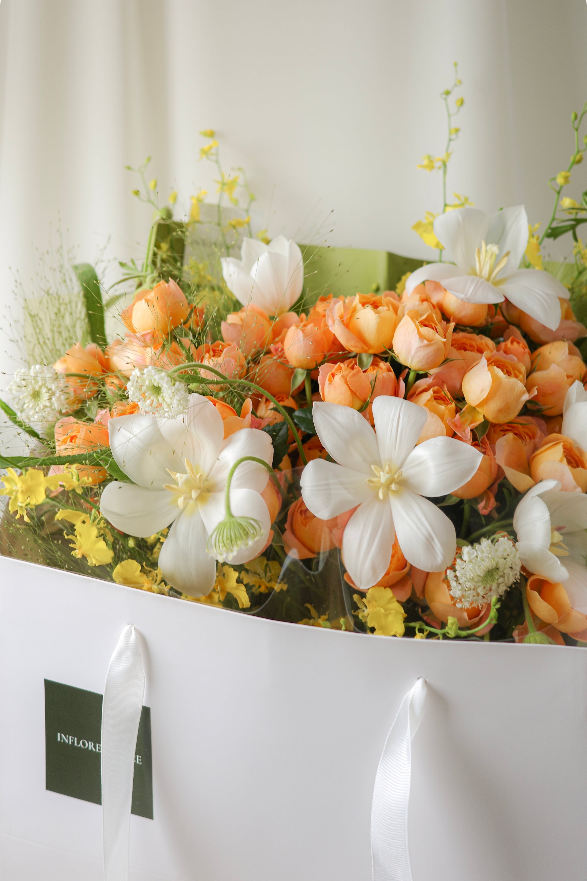 Fresh bouquet of orange roses, white blooms, and yellow accents with airy blooms, a cheerful arrangement perfect for birthdays and celebrations.